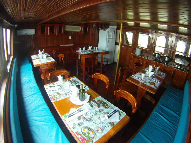 Refeitório interno do barco Yemanjár com mesas postas