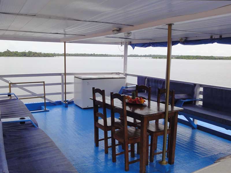 Deck superior do barco Yemanjár com mesa e vista para o rio